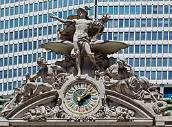 A large clock and stone sculptural group adorning the building's facade