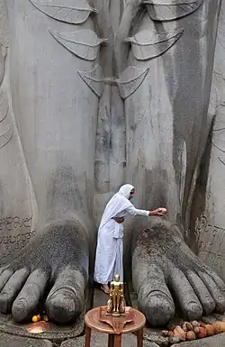 A Jain woman making an offering at the feet of Bahubali Gomateswara at Shravanabelagola, Karnataka