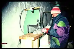 Scientist standing at a bench, sawing an ice core