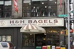 Storefront of H&H Bagel, awning at door and signage above reads "H&H Bagel - Like no other in the world."