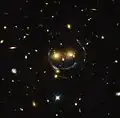"Smiley" image of galaxy cluster (SDSS J1038+4849) & gravitational lensing (an Einstein ring) (HST).[58]