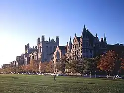 A view of neo-Gothic buildings in the background, with a grassy area in front