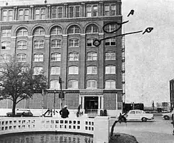 A photograph of the Texas School Book Depository, showing its view from a witness of John F. Kennedy's assassination. The window from the sixth floor is marked A, and another window from the fifth floor is marked B.