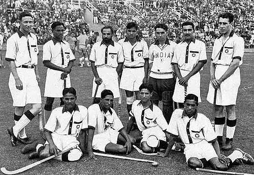 Indian hockey team, captained by Dhyan Chand (standing second from left), after winning the finals at the 1936 Summer Olympics – their third of six consecutive Olympic golds
