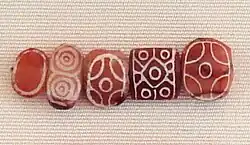 Indian carnelian beads with white design, etched in white with an alkali through a heat process, imported to Susa in 2400–2100 BC. Found in the tell of the Susa acropolis. Louvre Museum, reference Sb 17751.[63][64] These beads are identical with beads found in the Indus Civilization site of Dholavira.[65]