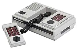 rectangular gaming console with numerical gamepads connected with short, black spirals