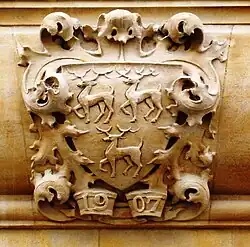 A carved stone crest of three stags (two above one) facing left, with their front right feet raised; below, the date "1907"