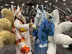 Two people wearing costumes resembling kitsune, foxes with masks and multiple tails