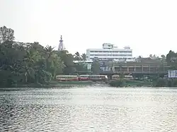 View across a lake of buses, trees and an urban skyline