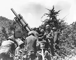 A group of soldiers readying a large gun in some brush