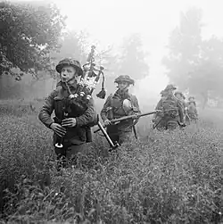 Bagpiper leading a line of soldiers though thigh-high growth