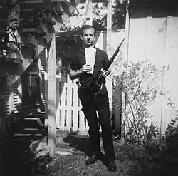 Oswald is pictured posing in a backyard. He holds a rifle in his left hand and a leftist publication in his right.