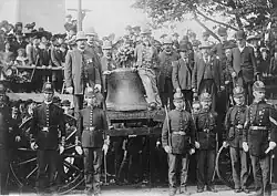 The Liberty Bell on a wagon; a number of people, including policemen, pose with it.
