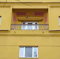 Portion of yellow apartment house with small balcony