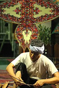 Making a traditional Wau jala budi kite in Malaysia. The bamboo frame is covered with plain paper and then decorated with multiple layers of shaped paper and foil.