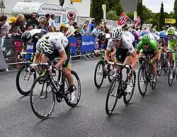 A number of cyclists are pictured sprinting along a road with a crowd watching them