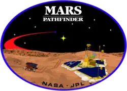 An image inside an oval, depicting two spacecraft, one a lander, and one a rover, on the surface of Mars. The words "Mars Pathfinder" are written on the top and the words "NASA&nbsp;· JPL" are written on the bottom.
