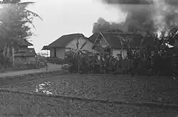Soldiers run into a kampong, where a number of houses are on fire, 1946.