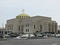 A large greyish stone building, topped with a golden dome.