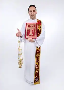 A picture of a full deacon with his vestments holding with a censer and the Gospel.