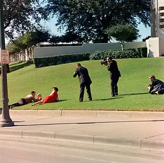 Witness hunker down on the grassy incline before the grassy knoll after the shooting