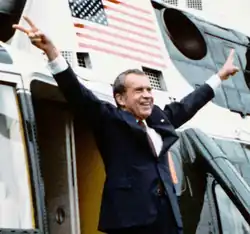 Nixon boarding a presidential helicopter as he leaves the White House, with outstretched arms flashing double V-signs