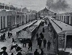 Several workers stand among trains and buildings with shovels in their hands