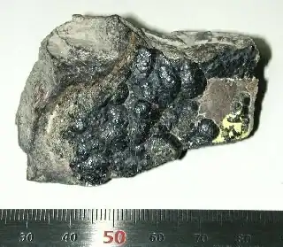 A shiny gray 5-centimeter piece of matter with a rough surface.