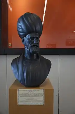 Photograph of a bust, stored at a museum, of a bearded and turbaned man