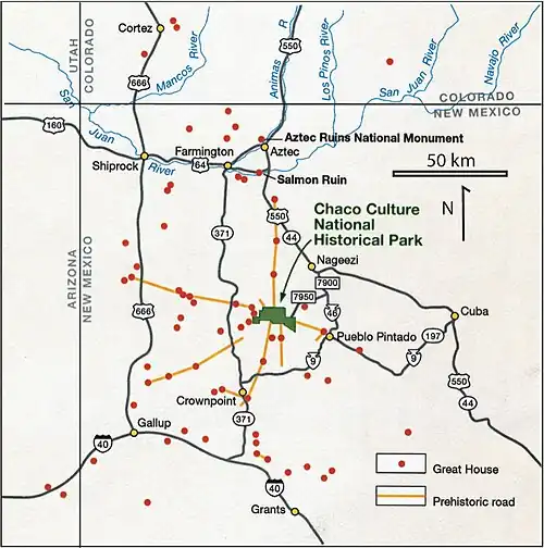 Large square map of northwestern New Mexico and neighboring parts of, clockwise from left, western Arizona, southeastern Utah, and southwestern Colorado. The map region has a green and blocky rectangular-crescent area at its center labeled "Chaco Culture National Historical Park". Radiating from the green region are seven segmented gold lines: "[p]rehistoric roads", each several dozen kilometers in length when measured according to the map scale factor. Roughly seventy red dots mark the location of "Great House[s]"; they are widely spread across the map, many of them far from the green area, near the extremes of the map, more than one hundred kilometers from the green area. Two proceed roughly south, one southwest, one northwest, one straight north, and the last to the southeast. Yellow dots mark the location of modern settlements: "Shiprock", "Cortez", "Farmington", and "Aztec" to the northwest and north; "Nageezi", "Cuba", and "Pueblo Pintado" to the northeast and east; "Grants", "Crownpoint", and "Gallup" to the south and southwest. They are connected by a network of gray lines marking various interstate and state highways. A fan of thin blue lines along the northern margins of the map depict the San Juan River and its communicants.