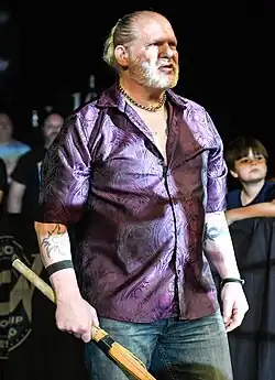 A color photograph of a man wearing a black t-shirt with yellow text and image