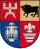 A coat of arms divided into four sections, the top left and bottom right of which are red, the bottom left of which is blue, and the top right of which is golden