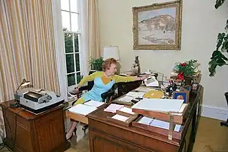 Nixon's secretary Rose Mary Woods demonstrating the implausible "Rose Mary Stretch" reaching backwards to pick up the phone