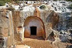 Rock-cut tomb entrance at Horvat Sumaqa with seven-branched menorahs carved on the façade