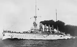 A large white warship with gray superstructure; several men are standing on the bow