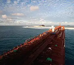 A large tanker ship with Clipperton Island in the background