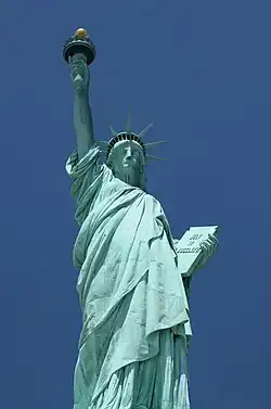 The Statue of Liberty, a large teal bronze sculpture on a stone pedestal