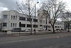 Long white building in winter, with trees in front