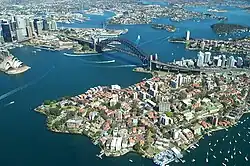 Sydney Harbour and Port Jackson displaying aerial views of the Sydney Harbour Bridge and the Sydney Opera House. The CBD is located to the far left of the photo.