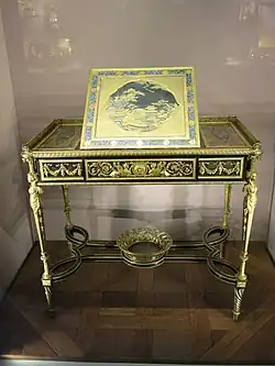 Writing table of Marie Antoinette; by Adam Weisweiler; 1784; oak, ebony and sycamore veneer, Japanese lacquer, steel, bronze gilt; 73.7 x 81. 2&nbsp;cm; Louvre[71]