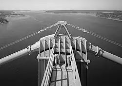 A thick steel cable passing over the top of a suspension bridge tower.
