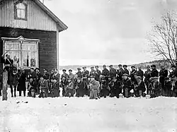 Around 40 troops of the paramilitary Red Guard pose to the camera next to a farmer's house on a field. One of them, their apparent commander, is on a horse.
