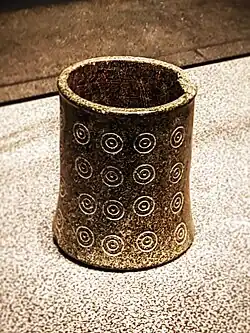 A brown cup with engraved concentric circles