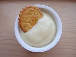 vanilla pudding in a bowl, with a cookie
