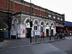 A white building with a rectangular, white sign reading "Vauxhall" in black letters and four bicycles in front all under a grey sky