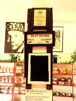 A selection of baked goods on shelves, next to a photograph of a middle-aged black man on the wall