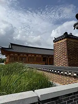 A photo of Yeonhwa-jeong Library, showing a traditional Korean building with a tiled roof under a blue sky.