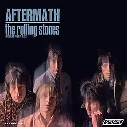 A colour photo depicting two band members in front of the other three, set against a blurred black background