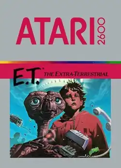 Artwork of a grey, vertical rectangular box. The top half reads "Atari 2600. E.T.* The Extra-Terrestrial". The bottom half displays a drawn image of a brown alien with a large head and long neck beside a young boy in a red, hooded jacket.