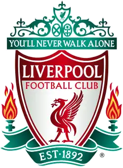 The words "Liverpool Football Club" are in the centre of a pennant, with flames either side. The words "You'll Never Walk Alone" adorn the top of the emblem in a green design, "EST 1892" is at the bottom